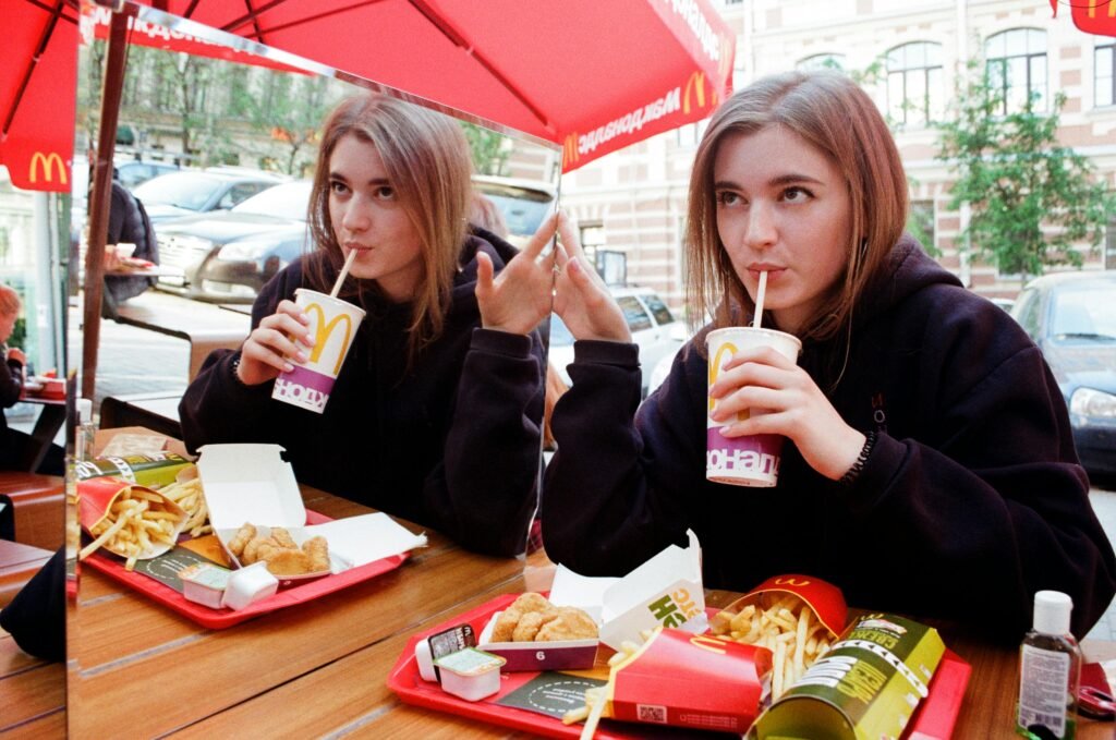 Young woman sipping soda at McDonald's with fries and nuggets.