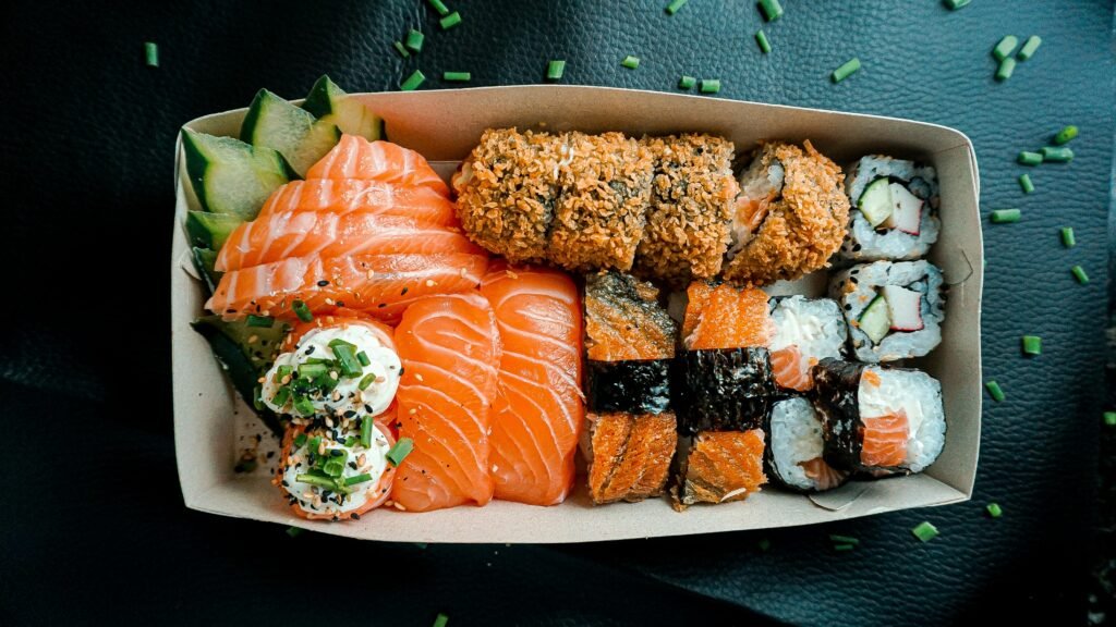 A mouth-watering assortment of sushi featuring nigiri, sashimi, and rolls in a takeout box.