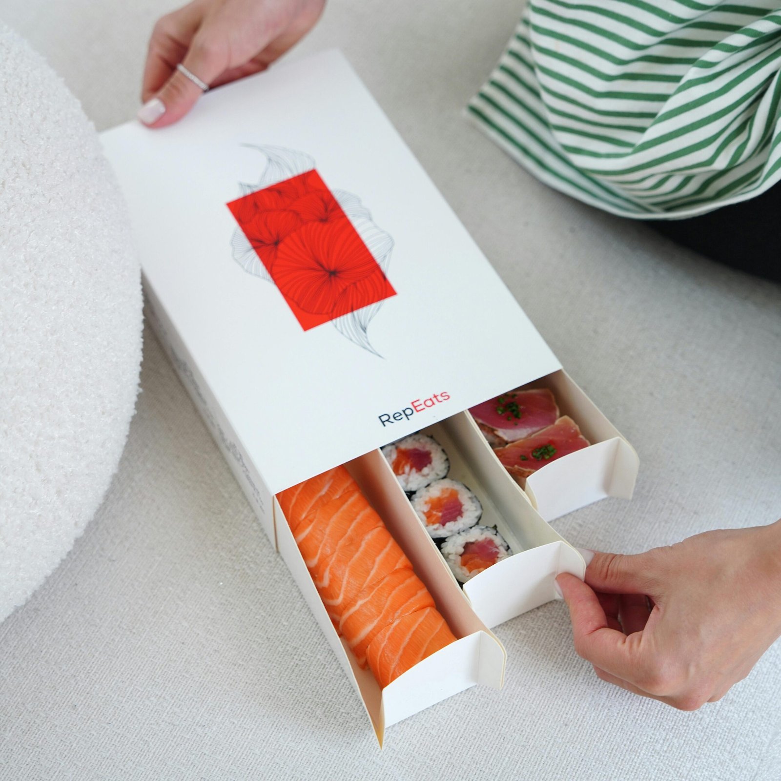 Close-up of a stylish sushi box featuring assorted fresh sushi pieces held by a woman.